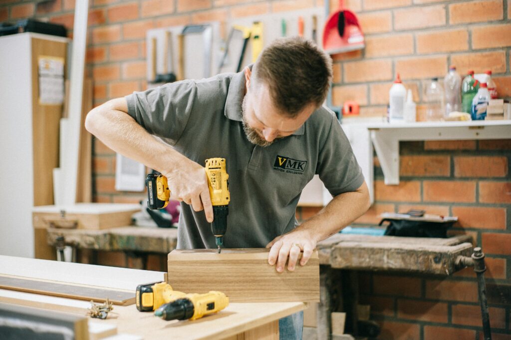 pexels-photo-28513057-28513057 A carpenter working with a drill in a well-equipped workshop.